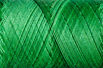 The green cotton thread is tightly wound on a bobbin, background image.