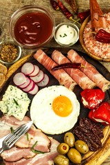 Fried egg on a wooden board. A hearty breakfast with ham and vegetables. Eggs and ham.