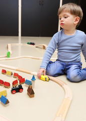 Ein kleiner Junge spielt mit einer Holzeisenbahn