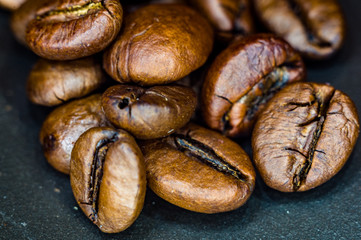 Brown roasted coffee beans on black background, close up, macro