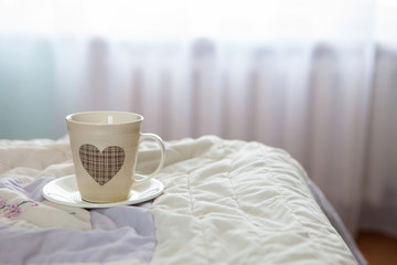 morning cup of coffee on the background of the bed and the window