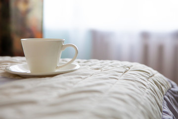 morning cup of coffee on the background of the bed and the window