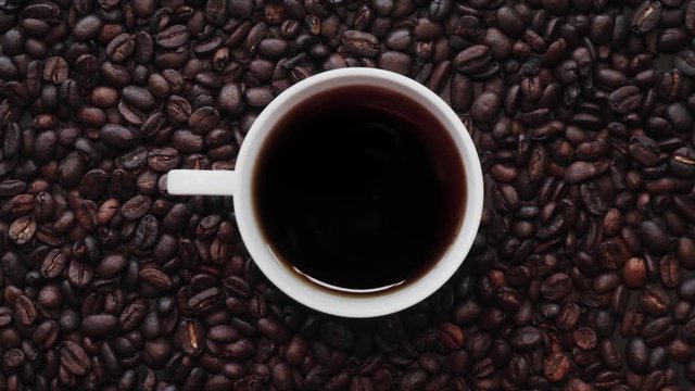 Loopable Cinemagraph of Cup of Coffee among Coffee Beans. Top View