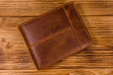 Closed brown leather wallet on wooden table. Top view