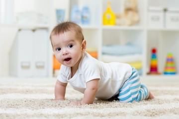 funny baby boy crawling on floor in nursery or at home