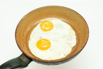 fried eggs from two eggs in a pan isolated on white background