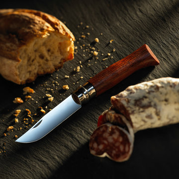 traditional hiking knife with bread and sausage on slate table