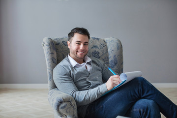 Man psychologist being ready to take notes sitting on the couch.