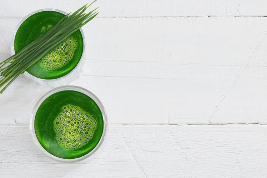 Healthy ingredients for detox, wheatgrass juice with young shoots of the wheat plant isolated on white background with copy space