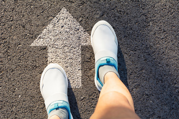 Fototapeta premium Top view of man wearing white shoes choosing a way marked with white arrows. Chooses the right path concept.