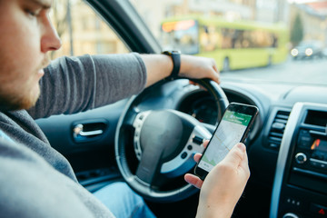 man hands on steering wheel using phone as navigator