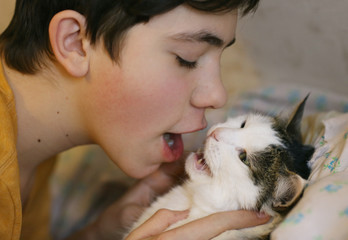 teenager boy with cat kissing hug photo