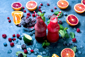 Berry smoothie with oranges and mint, healthy vitamin drink in bottles, refreshing juicy cocktail