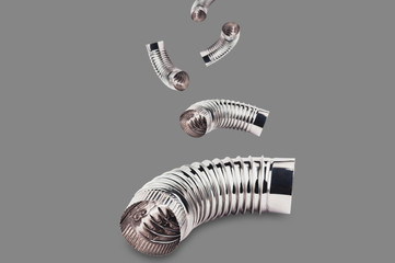 Falling chrome corrugated elbows of pipes for air, water, oil or gas on gray background