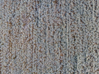 Aerial view of agricultural field covered with hoarfrost on cold winter morning.