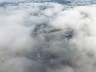 Aerial view of rural landscape in Switzerland covered with fog. Cold morning in winter with beautiful light. View from above the clouds with impressive sunlight.