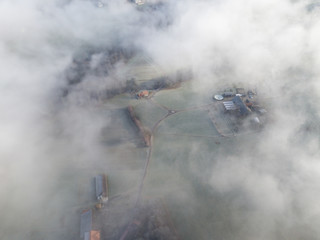 Aerial view of rural landscape in Switzerland covered with fog. Cold morning in winter with beautiful light. View from above the clouds with impressive sunlight.