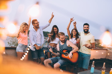 Group of happy friends having party on rooftop