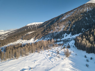 Fototapeta na wymiar Aerial view of snow covered valley on winter evening. Goms in Switzerland during winter with snow covered terrain.