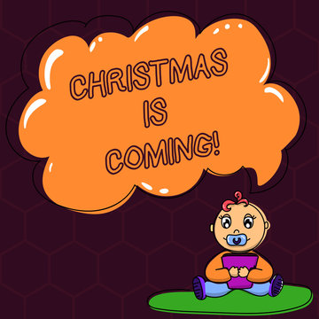Text sign showing Christmas Is Coming. Conceptual photo annual Christian festival celebrating Christs birth here Baby Sitting on Rug with Pacifier Book and Blank Color Cloud Speech Bubble