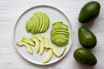 Whole and chopped avocados, top view. Overhead, from above, flat lay.