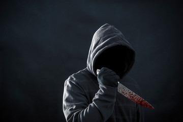 Hooded man with bloody knife in the dark  - Powered by Adobe
