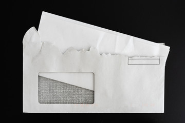 top view of folded letter in torn open envelope on black background
