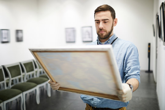 Waist up portrait of modern bearded man buying picture in art gallery, copy space