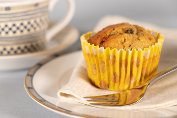Banana chocolate chip muffin on side plate, light blue background, with shallow depth of field.