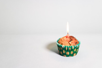 Banana chocolate chip muffin with birthday candle on white background, with shallow depth of field.