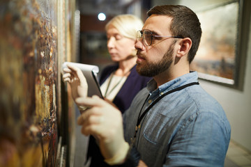 Waist up portrait of two museum workers inspecting painting for restoration, copy space
