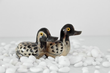 Valentine's day concept. Couple in love, just married or honeymoon concept. Couple of stone mandarin ducks toy looking in the same direction, with white pebbles.