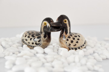 Valentine's day concept. Couple in love, just married or honeymoon concept. Couple of stone mandarin ducks toy with white pebbles.