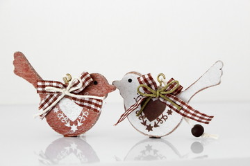 Valentine's day concept. Couple in love, just married or honeymoon concept. Couple of wooden birds looking at each other with painted hearts and fabric bows with reflection.