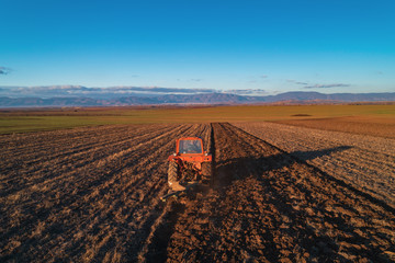 Fototapeta premium Tractor cultivating field at spring