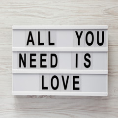 'All you need is love' words on modern board over white wooden surface, top view. From above, flat lay, overhead.