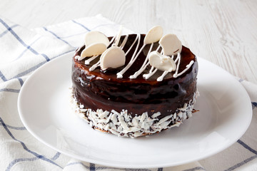 Homemade chocolate cherry cake on plate on a white wooden table, side view. Closeup.