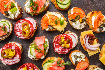 Assorted spanish tapas with fish, sausage, cheese and vegetables. Dark background, top view.