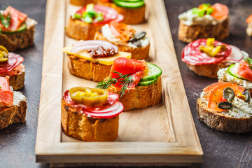 Assorted spanish tapas with fish, sausage, cheese and vegetables. Dark background, top view.