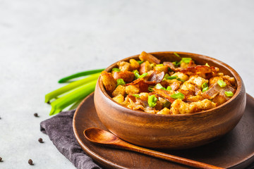 Spanish migas with pork and green onion in wooden bowl on white background.