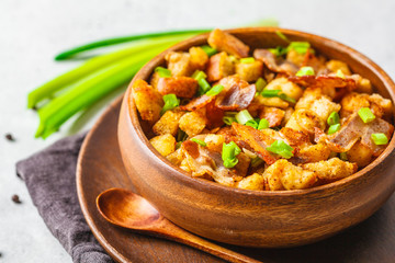 Spanish migas with pork and green onion in wooden bowl on white background.
