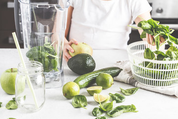 Child cooking spinach apple cucumber smoothie. Healthy plant based food concept.
