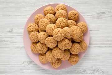 Almond cookies on pink plate on a white wooden surface, overhead view. Flat lay, top view.
