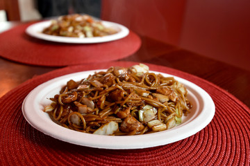 Asian noodles with vegetables and chicken served on plate.