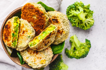 Green broccoli burgers in coconut shell dish on white background, top view.
