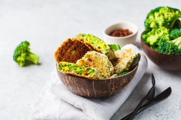 Green broccoli burgers in coconut shell dish on white background.