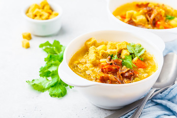 Split pea soup with smoked bacon and crackers in white plate.