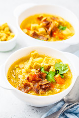 Split pea soup with smoked bacon and crackers in white plate.