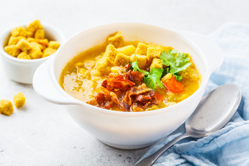 Split pea soup with smoked bacon and crackers in white plate.