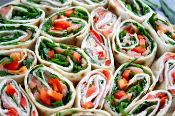 Kolorowe roladki z tortilli, rukoli, papryki, wędzonego łososia lub szynki parmeńskiej